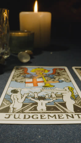 Vertical-Video-Close-Up-Shot-Of-Person-Giving-Tarot-Card-Reading-Laying-Down-The-Judgement-Card-On-Table